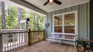 A wooden deck with a white bench and a small table, surrounded by a white railing.