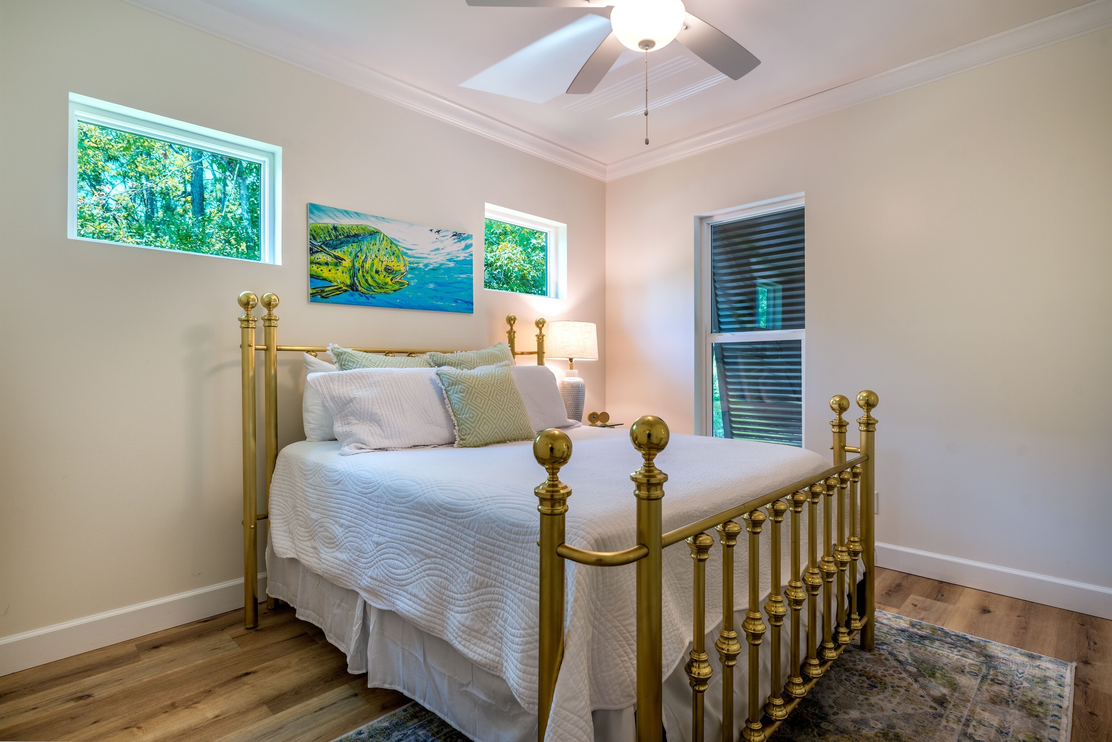 A bedroom with a bed, a ceiling fan, and two windows.