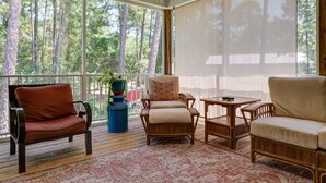 A covered porch with wicker furniture, a table, and a potted plant.