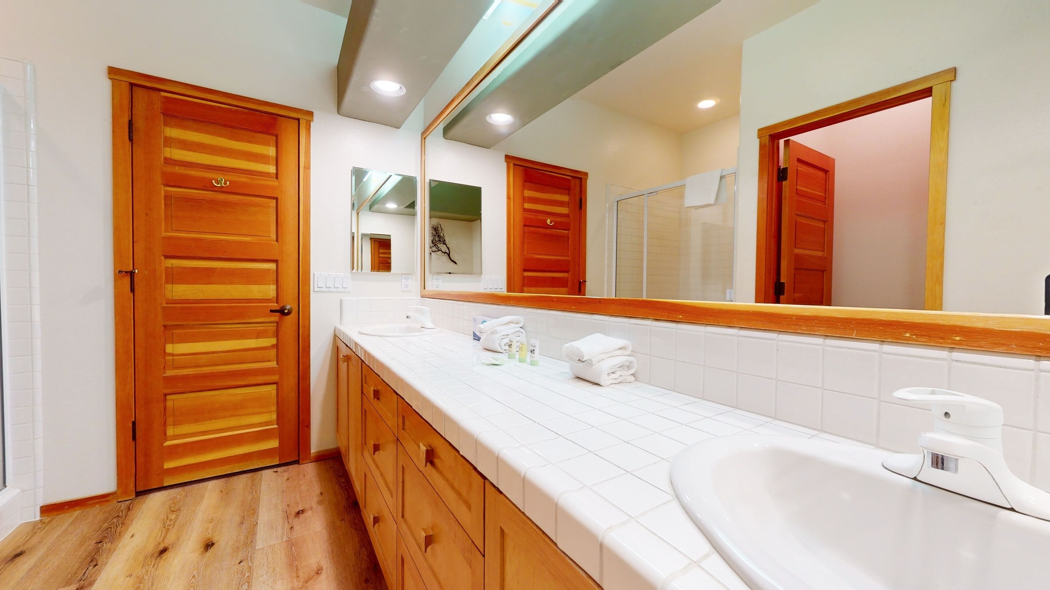 A bathroom with wooden doors, a white sink, and a large mirror.