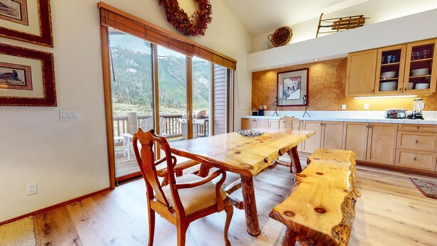 A spacious kitchen with wooden cabinets, a dining table, and a large window overlooking a scenic landscape.