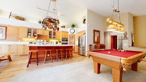 A spacious kitchen with wooden cabinets, a central island with stools, a built-in oven, and a refrigerator.