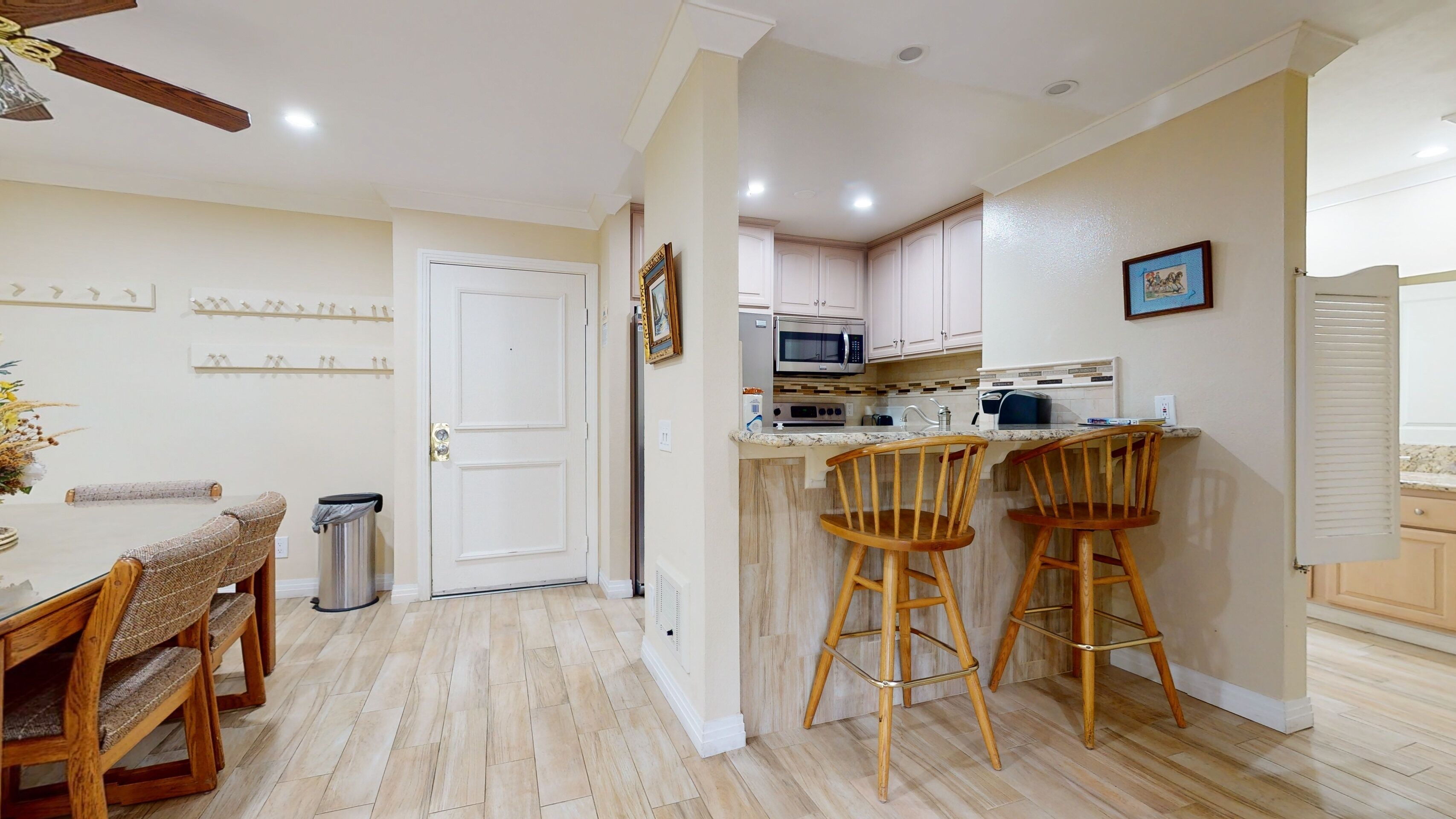 A modern kitchen with wooden flooring, a dining area with a table and chairs, and a small bar area with stools.