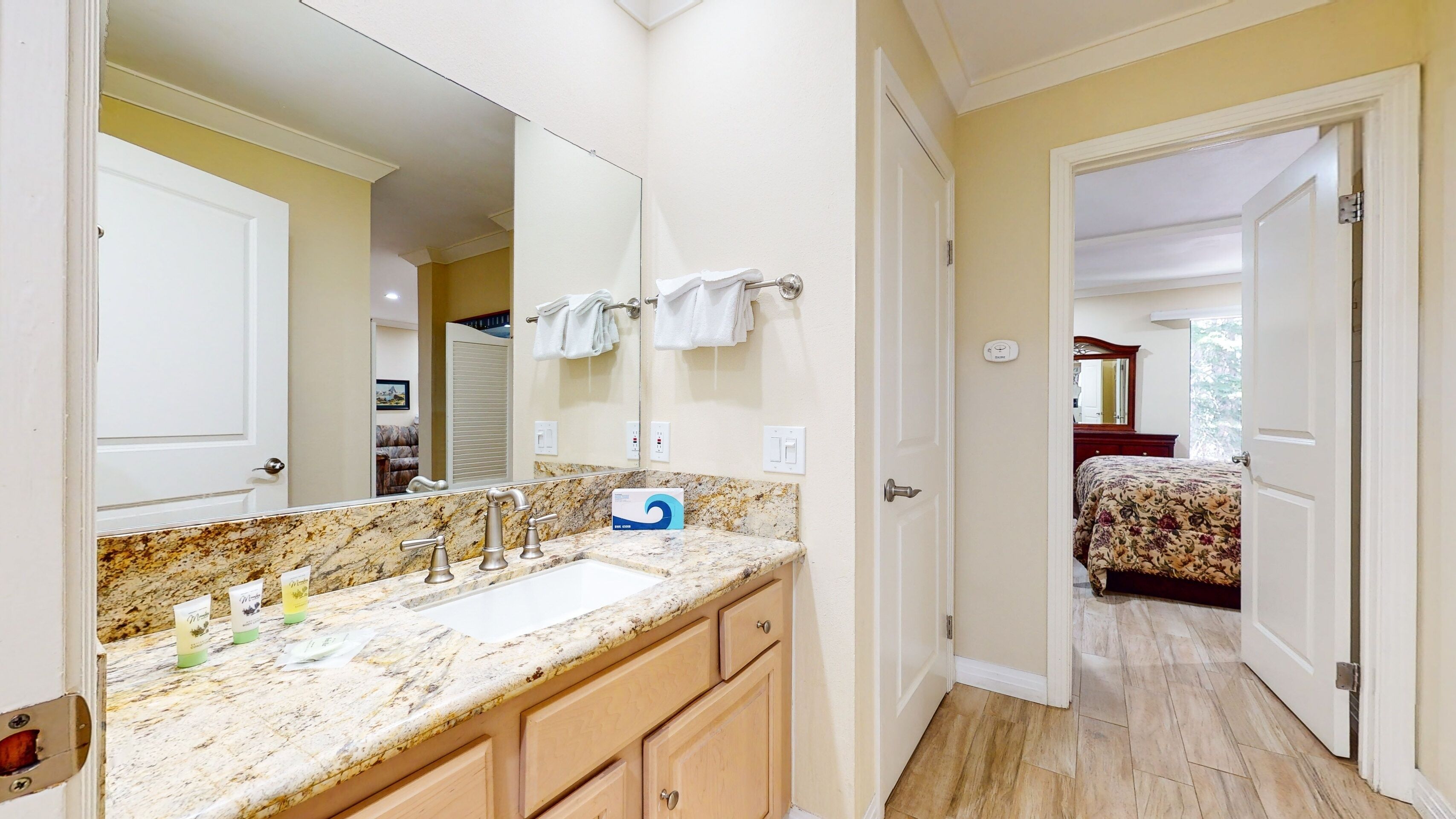A bathroom with a marble countertop, a large mirror, and a towel rack.
