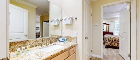 A bathroom with a marble countertop, a large mirror, and a towel rack.