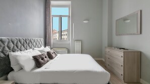 A modern bedroom with a large bed, a dresser, and a mirror on the wall. - Manzoni Apartment (Roma)