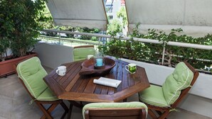A wooden table with four chairs, a bowl, a candle, and a green apple mug. - Stylish Athinas House in Kallithea (Kallithea)