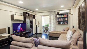 A living room with a television, sofa, and bookshelf. - Stylish Athinas House in Kallithea (Kallithea)