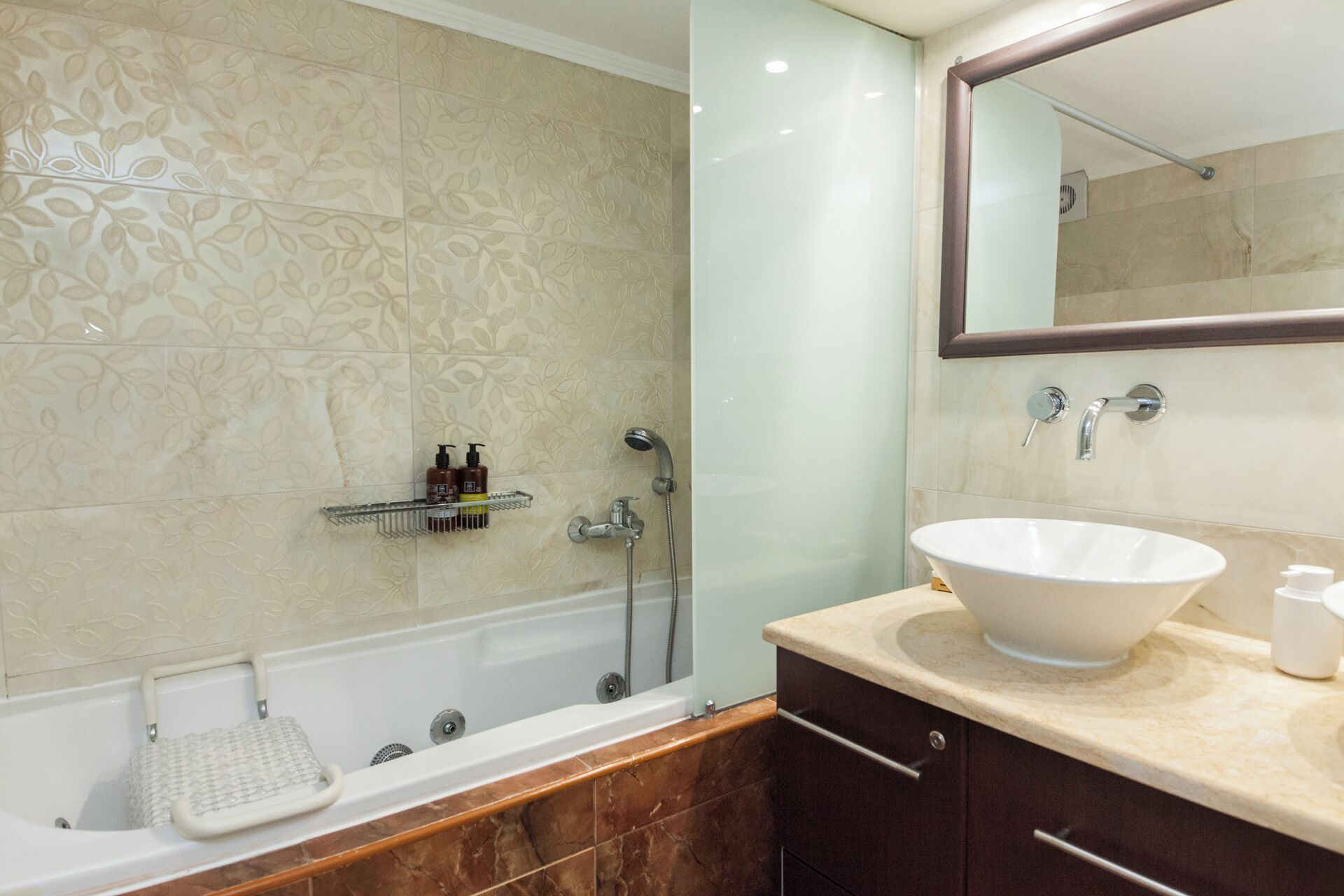 A modern bathroom with a bathtub, a glass-enclosed shower, and a vanity with a large sink.