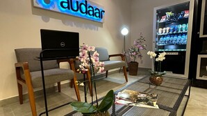 Una sala moderna con una laptop Dell sobre un soporte, un sofá, una mesa de centro con una revista y un acuario grande.