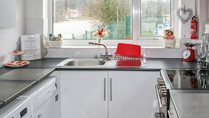 A kitchen with a window, a sink, a red dish rack, and a washing machine. - 2 bedroom accommodation in Ruswarp, near Whitby (Ruswarp, near Whitby)