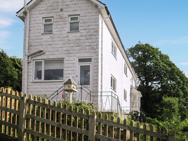 A white brick building with multiple windows and a small balcony.