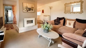A living room with a fireplace, a sofa, a coffee table with flowers, and a mirror on the wall. - 2 bedroom accommodation in Ruswarp, near Whitby (Ruswarp, near Whitby)