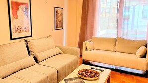 A living room with two beige sofas, a coffee table with a bowl of snacks, and a framed picture on the wall. - Grand apartment in Acropolis museum (Athina)