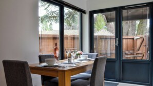 A dining area with a wooden table, four grey chairs, and a bottle of wine. - 1 bedroom accommodation in Aboyne (Aboyne)
