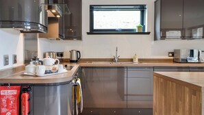 A modern kitchen with stainless steel appliances, a built-in oven, and a window above the sink. - 1 bedroom accommodation in Aboyne (Aboyne)