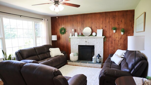 A living room with two brown leather sofas, a fireplace, and a ceiling fan.