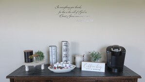 A coffee station with a coffee maker, mugs, and a sign saying "Coffee bar love is brewing".