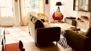 Een moderne woonkamer met een bank, fauteuils, een eettafel en een televisie.
