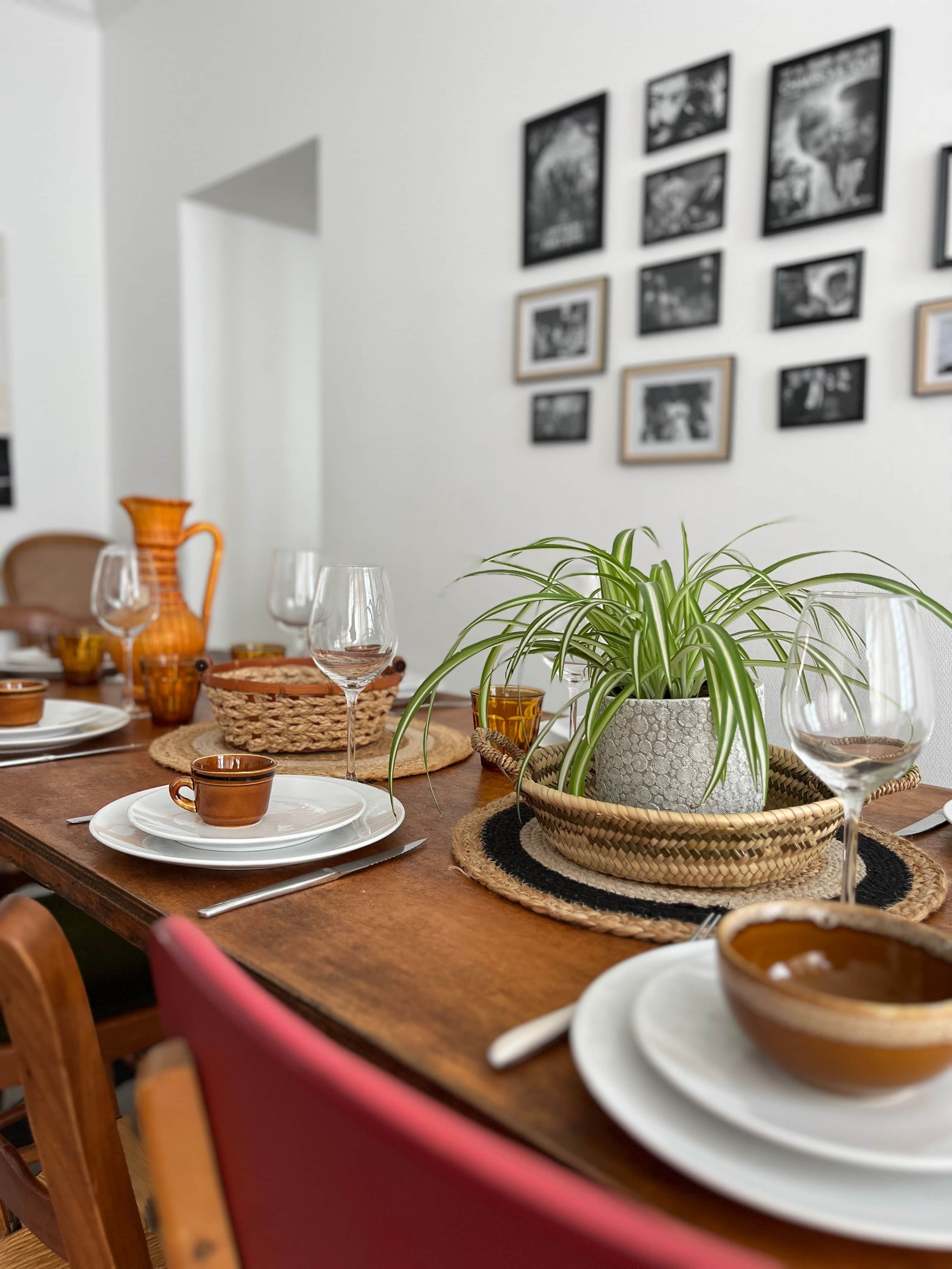 A dining table set with plates, glasses, and a potted plant.