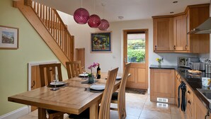 Un comedor con una mesa y sillas de madera, una escalera y armarios de madera.