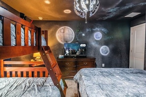 Un dormitorio con una litera, un aparador y un mural temático de Star Wars.