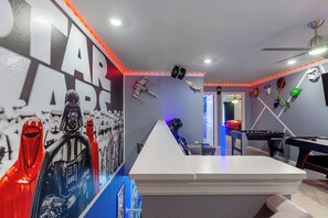 A room with Star Wars-themed decorations, including a large poster, lightsabers, and a ceiling fan.