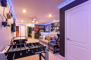 A room with a foosball table, a ceiling fan, Star Wars posters, and a Star Wars-themed arcade machine.