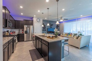 Enjoy meals and relaxation in this kitchen with a central island, sink, and ample counter space, flanked by cabinetry and stainless steel appliances.