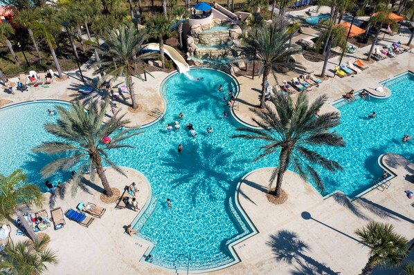 Enjoy a family-friendly pool experience with a water slide and multiple levels surrounded by palm trees.