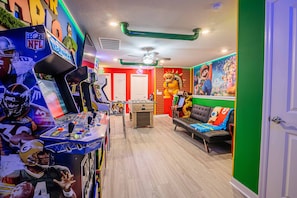 Quarto com mesa de futebol, sofá e um mural do Mario.