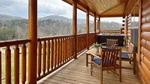 Une terrasse en bois offrant une vue sur une chaîne de montagnes boisées.