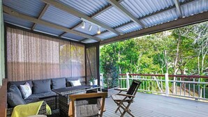 A covered outdoor seating area with a sofa, chairs, and a table.