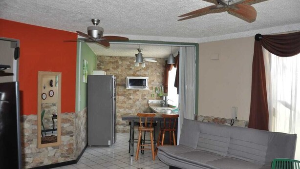 Un espacio habitable compacto con kitchenette, un sofá y un ventilador de techo.