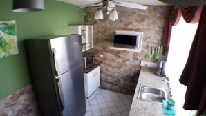 Una cocina compacta con refrigerador, microondas y ventilador de techo.