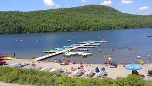 A lakeside beach with boats docked, a pier, and people swimming and sunbathing. - The JOFORD, Condo, 5 minutes from skiing, Sépaq with extras (bikes, paddles +) (Orford)