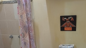 Une salle de bain avec une douche, des toilettes et une petite étagère où sont posées des serviettes.