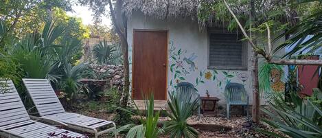 Un pequeño jardín con una puerta de madera, un banco y una silla.