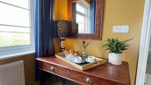 A wooden desk with a tray of pastries, a cup of coffee, and a potted plant. - Rame View - Double Bedroom with En-suite (Millbrook)