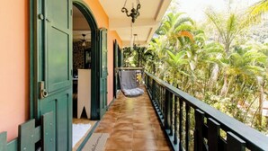 A balcony with a tiled floor, a hanging chair, and a view of tropical vegetation. - Accès Direct à la Plage - Suite Île (Itacuruçá)