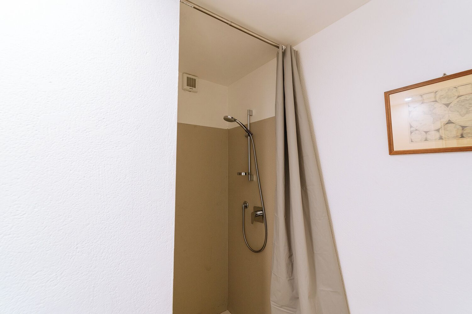 A bathroom with a shower, a towel rack, and a framed picture on the wall.