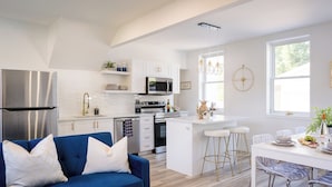 A modern kitchen with white cabinets, stainless steel appliances, and a blue sofa.