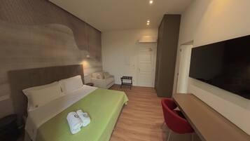 A hotel room with a bed, a desk, a chair, a television, and a door.