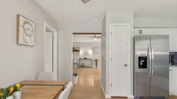 Une cuisine moderne dotée d’un réfrigérateur en acier inoxydable, d’un plancher en bois et d’un coin repas avec une table et des chaises.