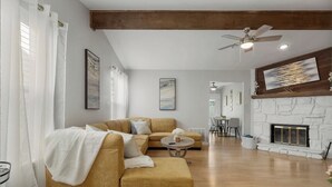 Un salon avec un canapé, un pouf et une cheminée.