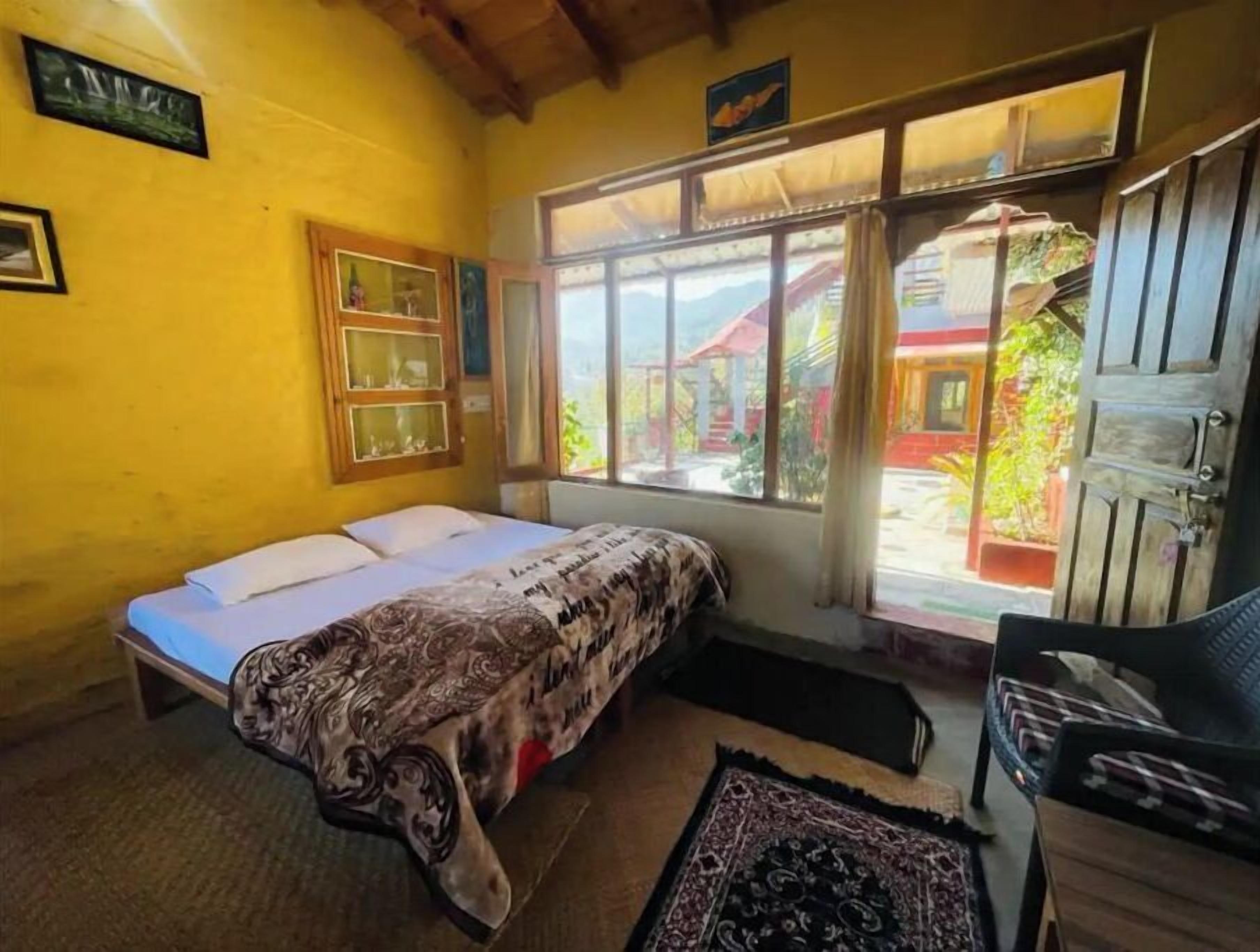 Een kamer met een bed, een stoel, een raam met uitzicht op een rood gebouw en een houten plafond.