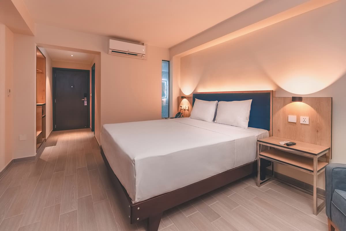 Une chambre d’hôtel avec un grand lit, des tables de chevet, un bureau et un appareil de climatisation.
