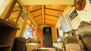 Una sala de estar acogedora con vigas de madera, una chimenea y un retrato en la pared.
