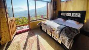 Ein Schlafzimmer mit einem Bett, einem Fenster mit Bergblick und einer Tür.