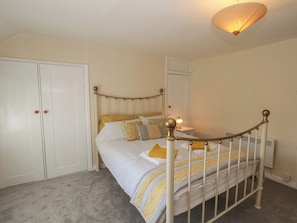 Ein Schlafzimmer mit Bett, Kleiderschrank, Nachttisch und Lampe.
